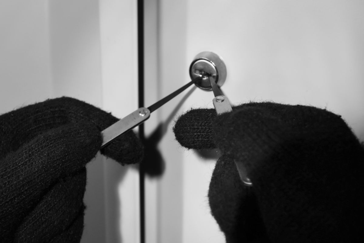 Gloved hands picking a door lock. Gloved hands picking a door lock.