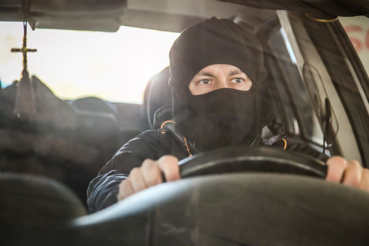 Masked driver gripping a steering wheel. Masked driver gripping a steering wheel.