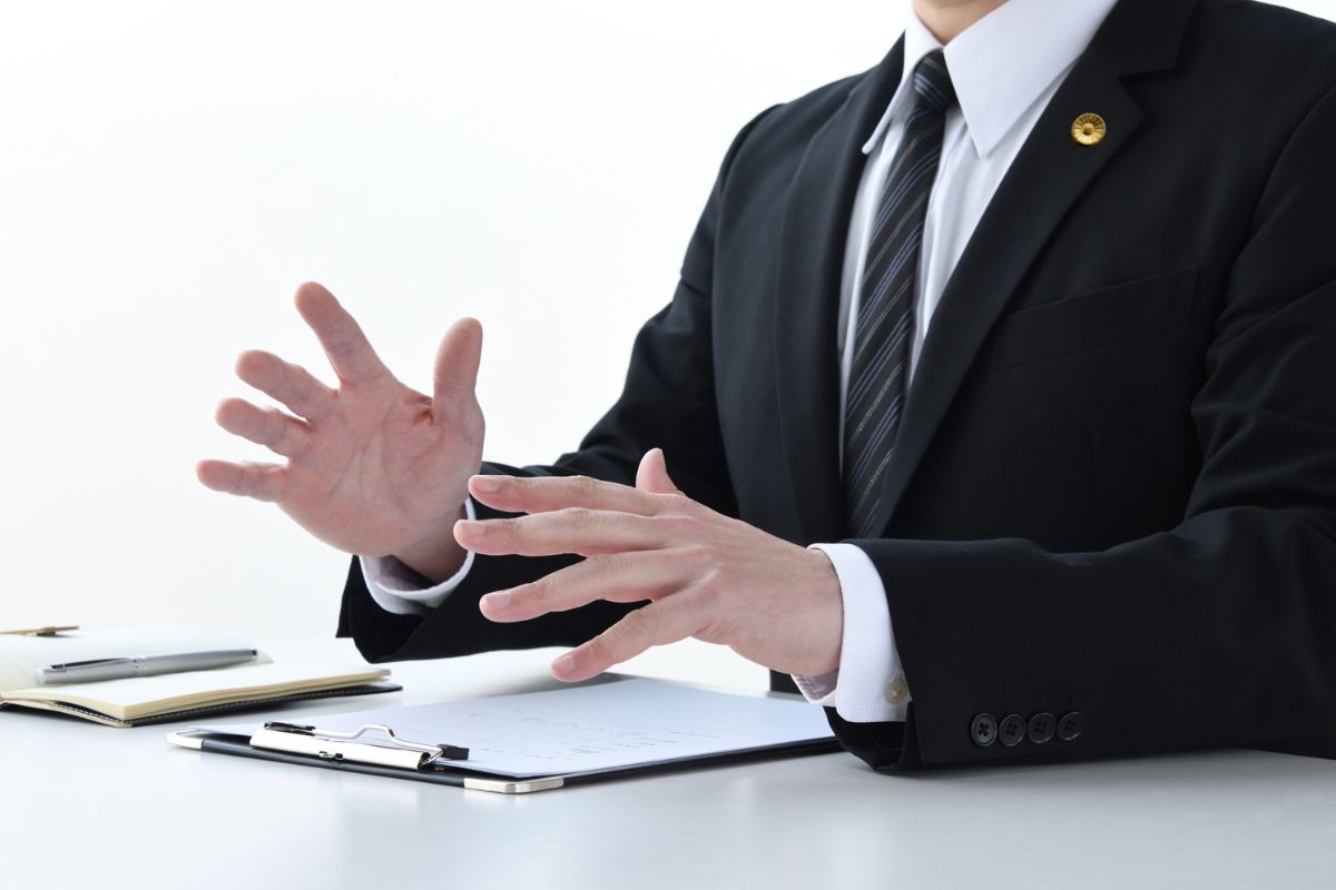 A lawyer gesturing while discussing a case at a desk. A lawyer gesturing while discussing a case at a desk.