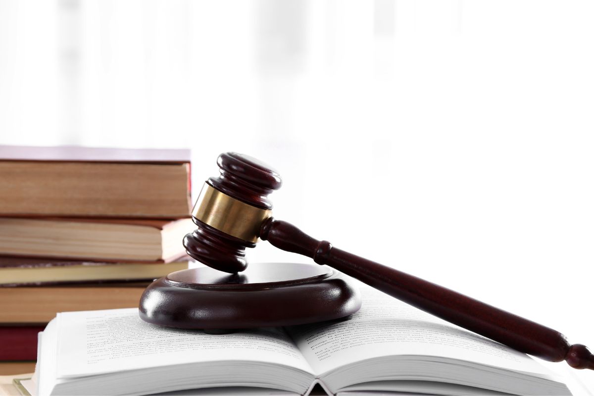 Gavel resting on an open law book beside stacked legal books. Gavel resting on an open law book beside stacked legal books.