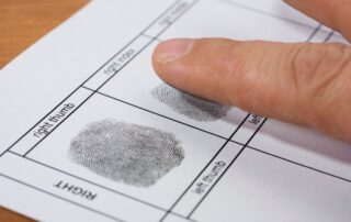 Man being fingerprinted by police during booking procedure.