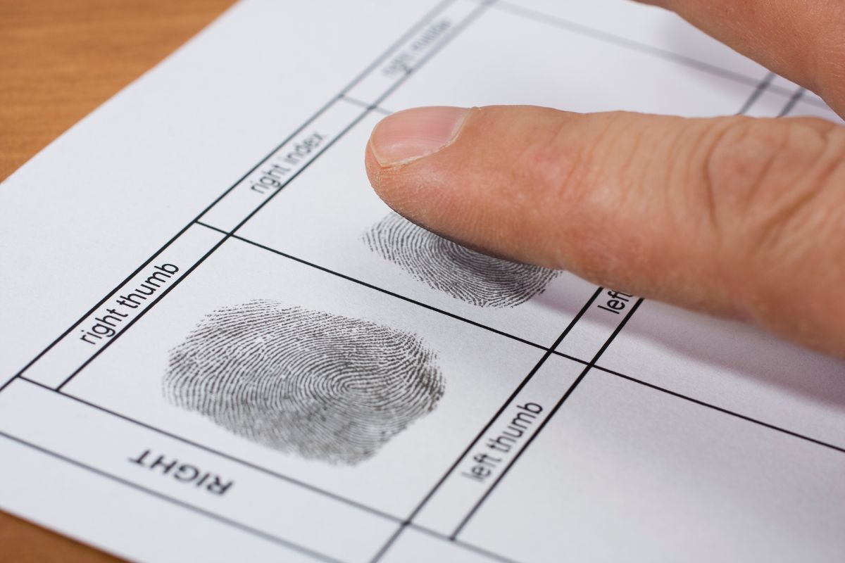 Man being fingerprinted by police during booking procedure.