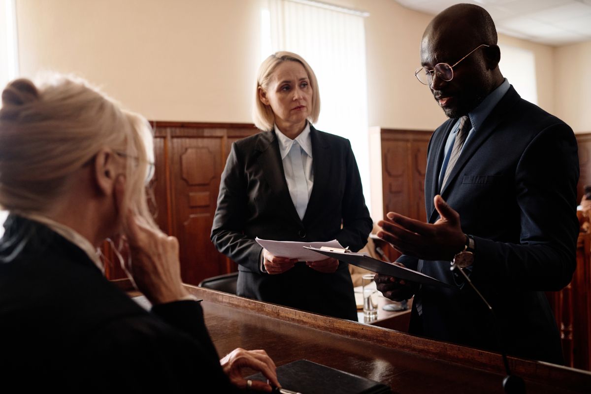 Defence and prosecution before judge during courtroom proceedings.