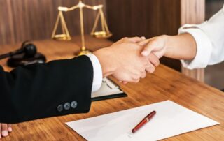 Lawyer consultant shaking hands with client in law firm.