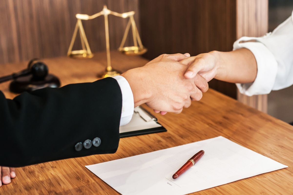 Lawyer consultant shaking hands with client in law firm.