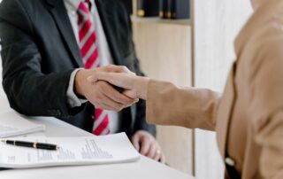 Lawyer and client shaking hands after signing a retainer agreement.