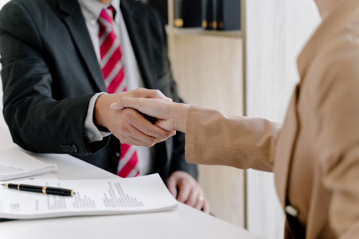 Lawyer and client shaking hands after signing a retainer agreement.