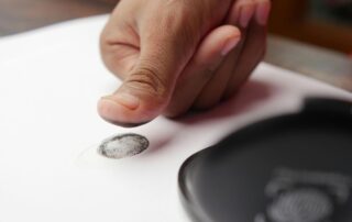 Close-up of a thumb making a fingerprint on paper.