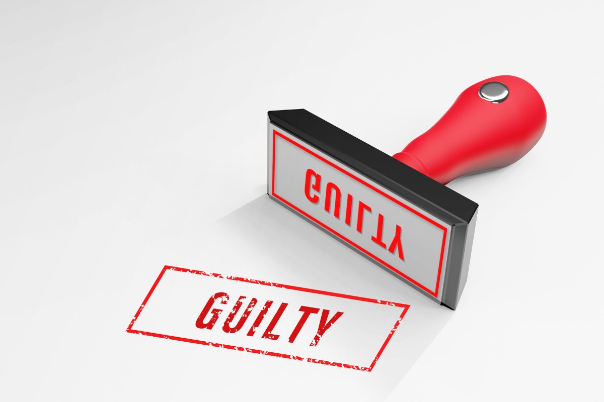 Red rubber stamp marking the word “GUILTY” on paper.