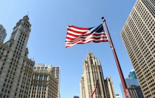 American flag flying among tall buildings in a city.