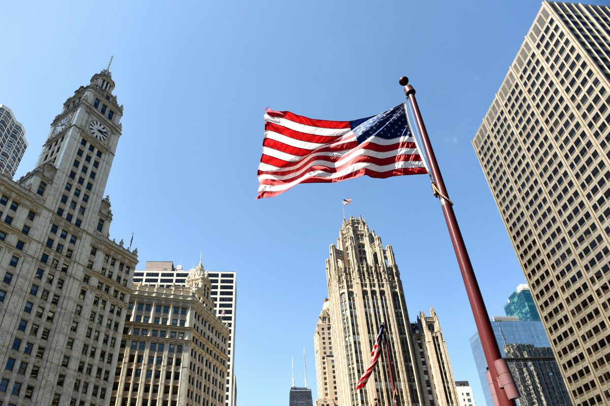American flag flying among tall buildings in a city.