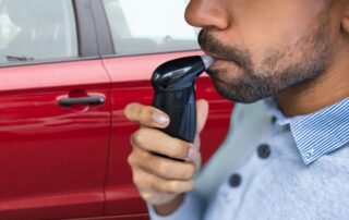 A man is using a breathalyzer device.