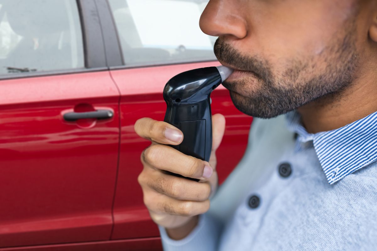 A man is using a breathalyzer device.