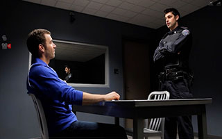 Police officer interrogating man across from table