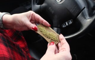 A person rolling marijuana in a car.