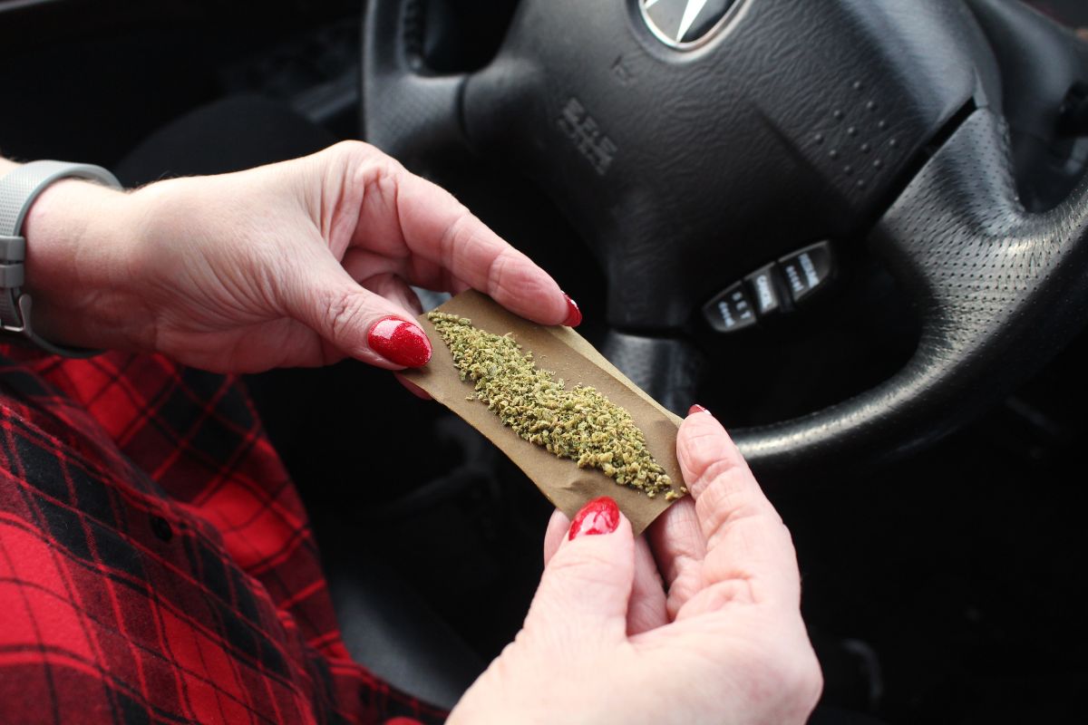 A person rolling marijuana in a car.