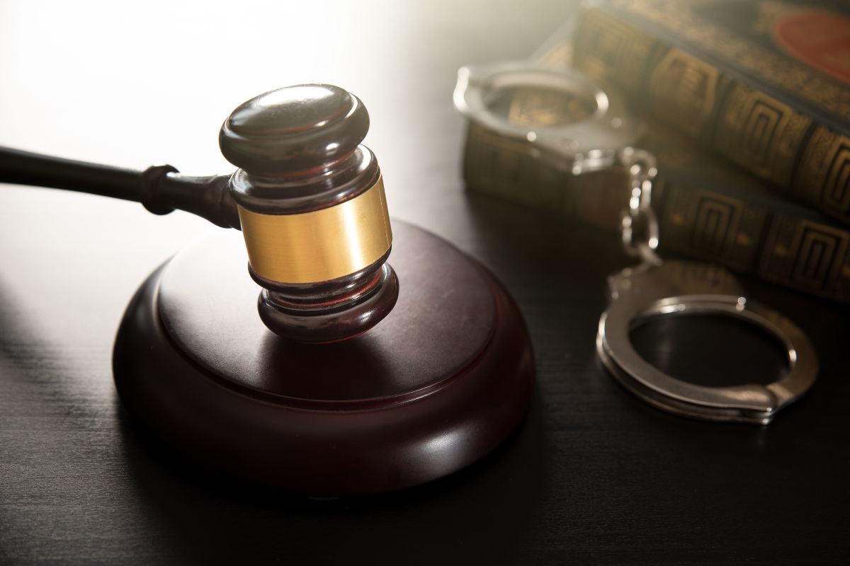 Judge’s gavel beside handcuffs and legal books.