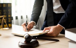 Lawyer writing in a book at a desk with a gavel and scales of justice.