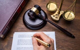 A judge writing on a legal document with a gavel, scales of justice, and a law book.