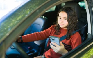A woman is driving while using her phone.