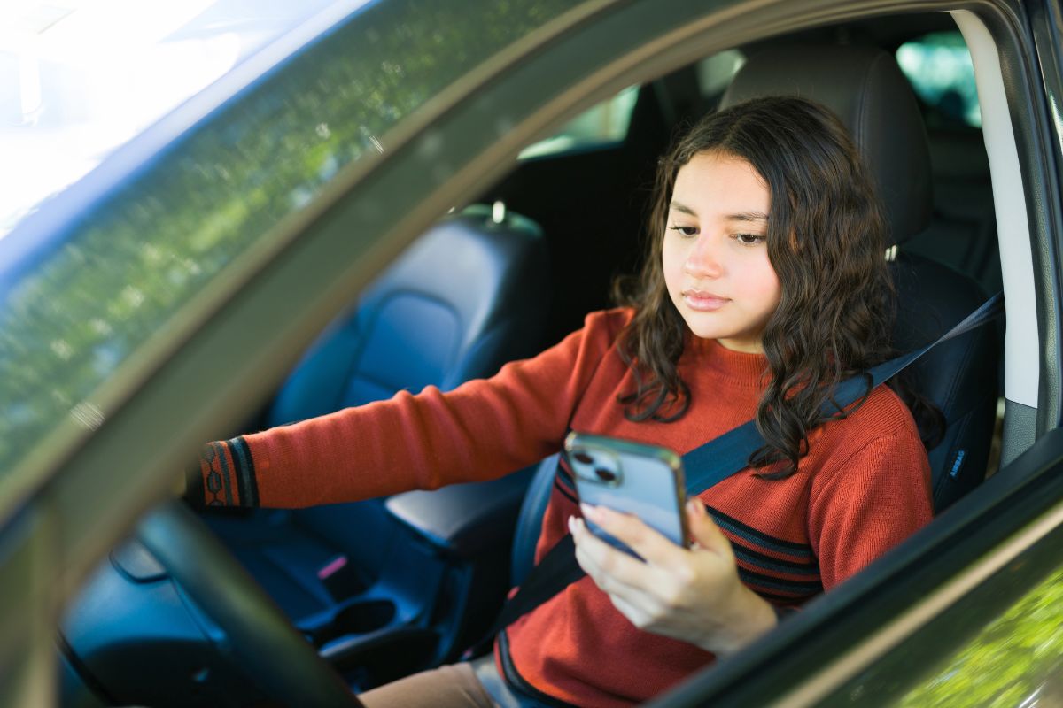 A woman is driving while using her phone.