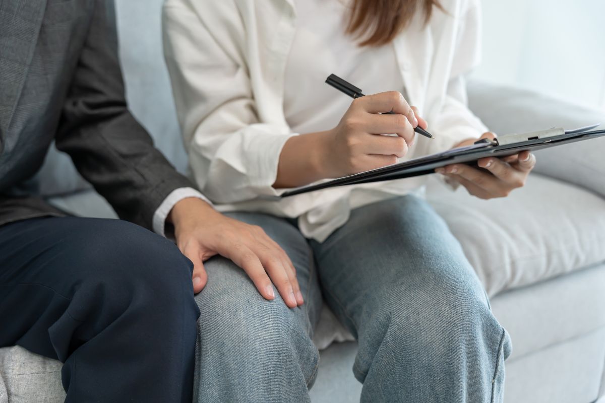 A man's hand rests inappropriately on a woman's leg.