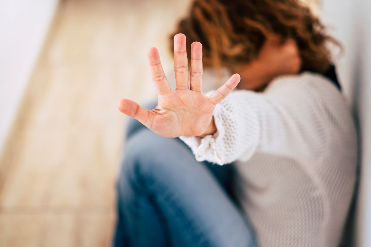 A woman sitting on the floor with her hand raised.