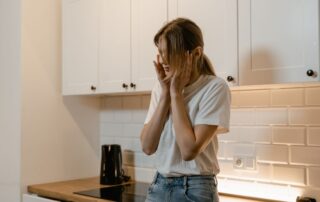 Distressed woman standing in a kitchen.