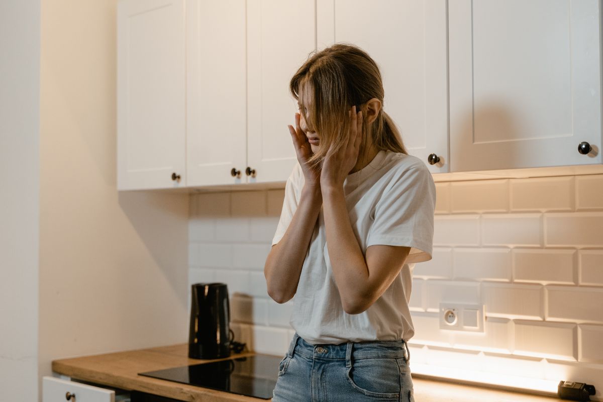 Distressed woman standing in a kitchen.