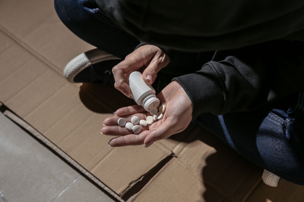 A man pouring white pills into their hand.