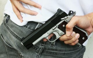 A man holding a handgun tucked into his waistband.