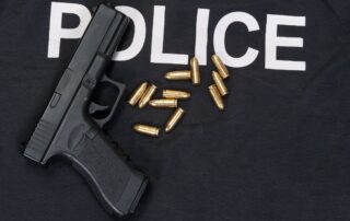 A handgun and bullets are placed on a police vest.