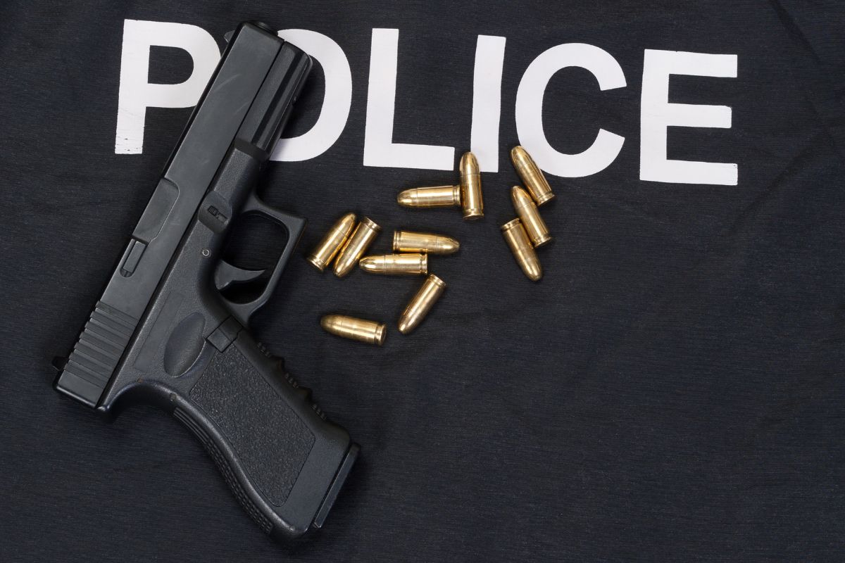 A handgun and bullets are placed on a police vest.