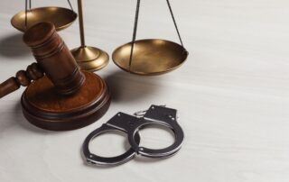 A judge’s gavel, scales of justice, and handcuffs.