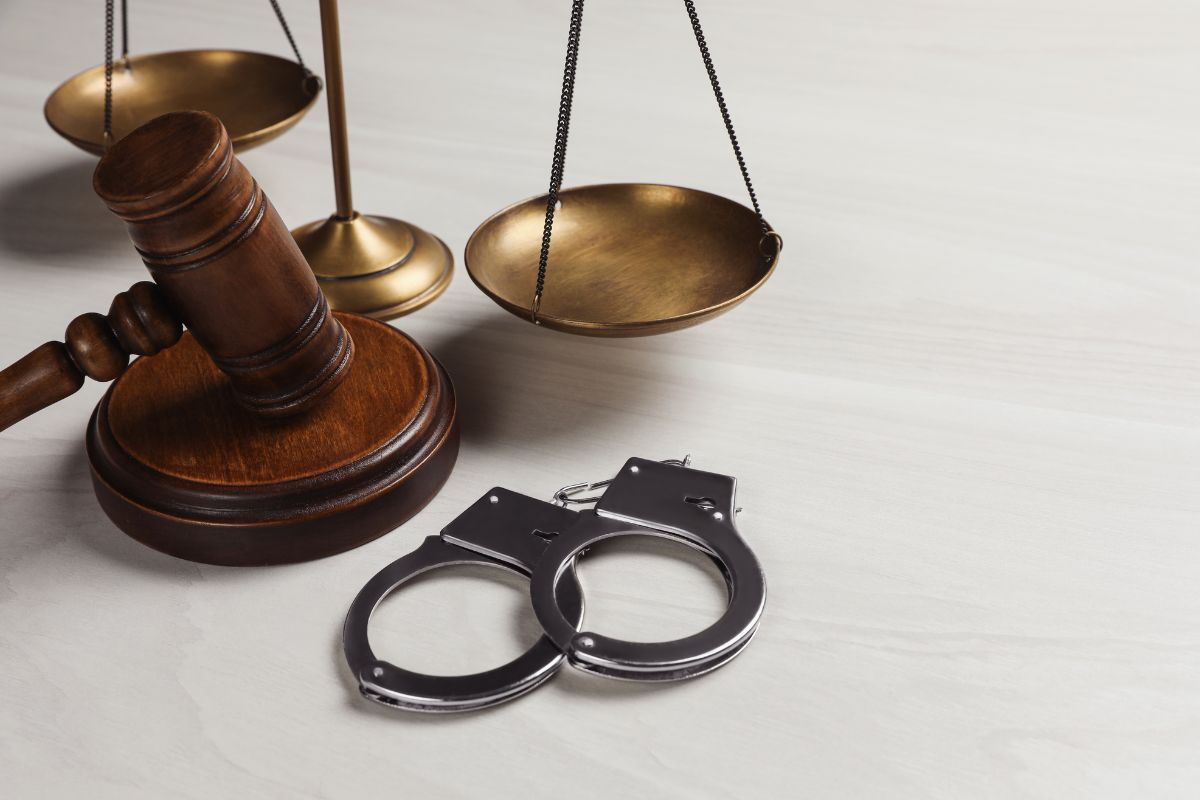 A judge’s gavel, scales of justice, and handcuffs.