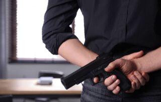 A man holding a handgun behind their back.