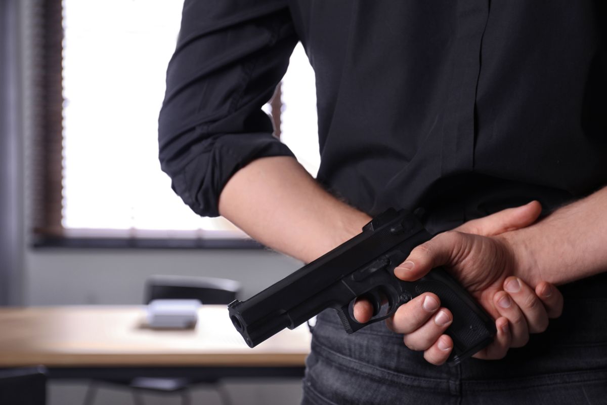 A man holding a handgun behind their back.