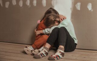 Two children hugging on the floor.