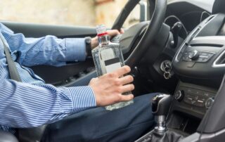 A driver holding a liquor bottle.