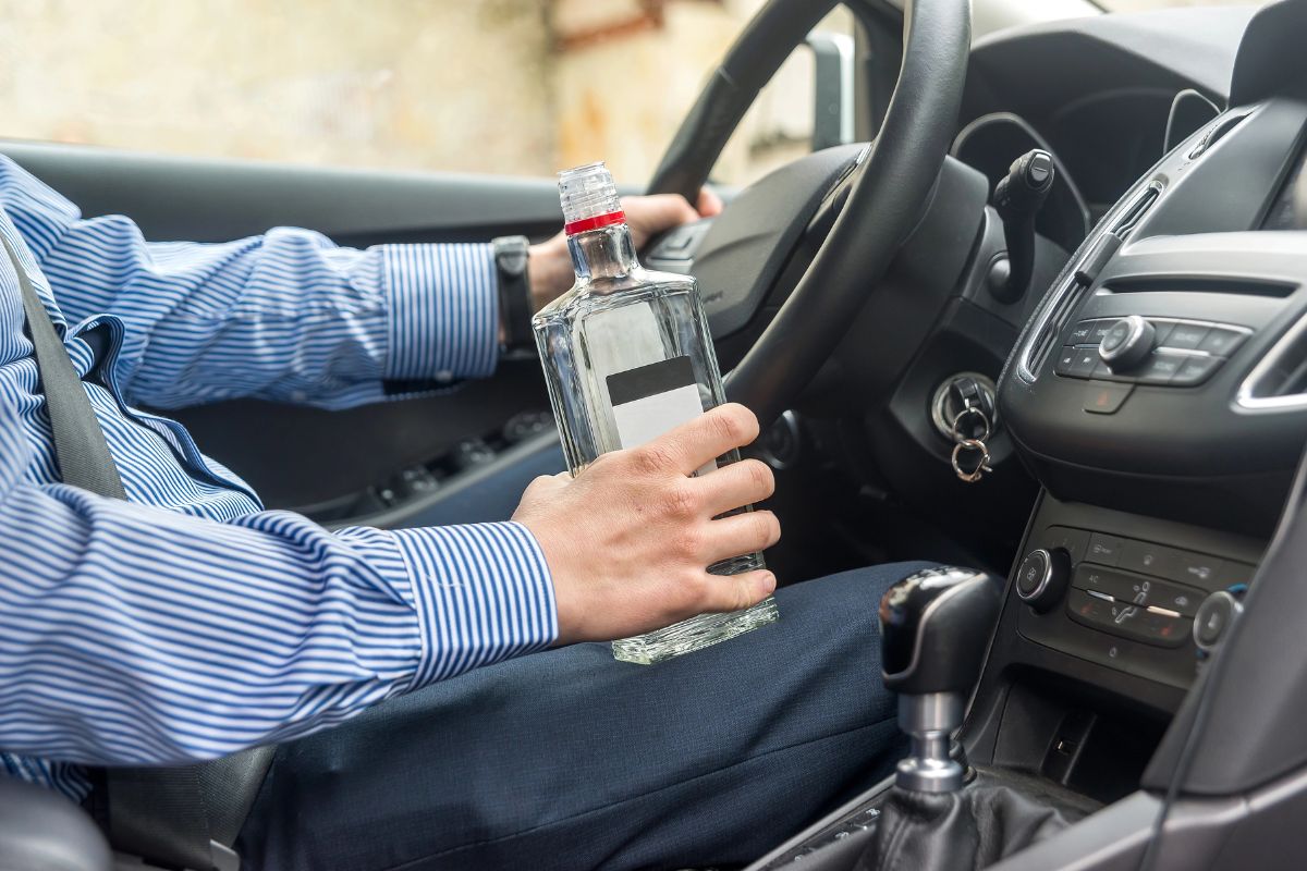 A driver holding a liquor bottle.