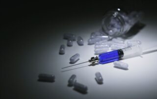A syringe and spilled capsules on a table.