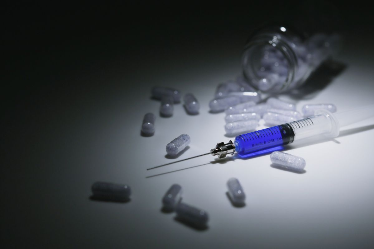 A syringe and spilled capsules on a table.