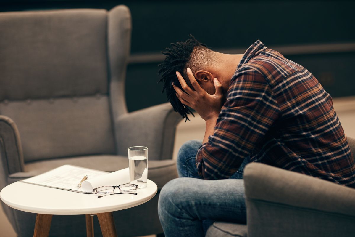 A man is sitting, looking distressed.