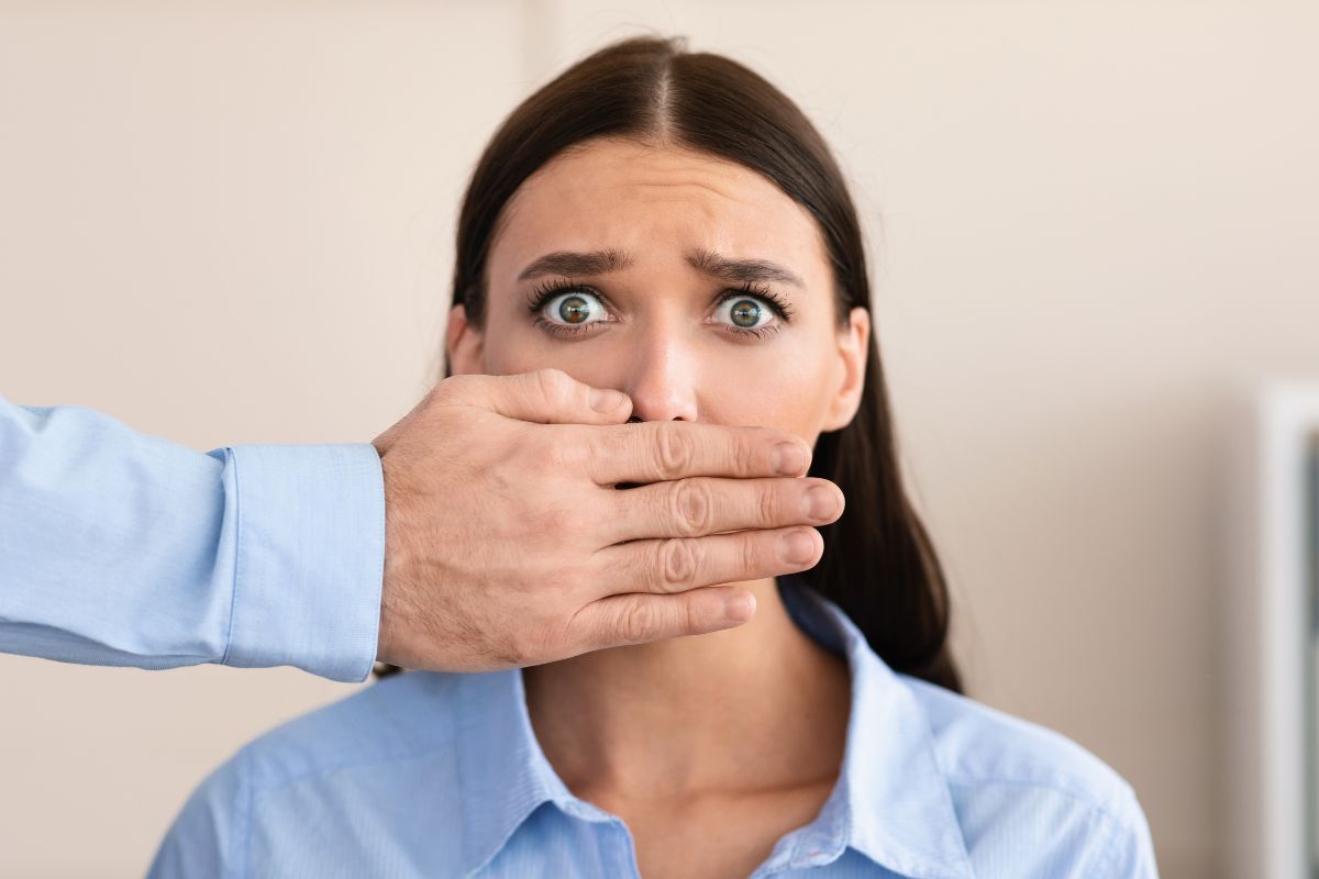 A frightened woman with a hand covering her mouth.