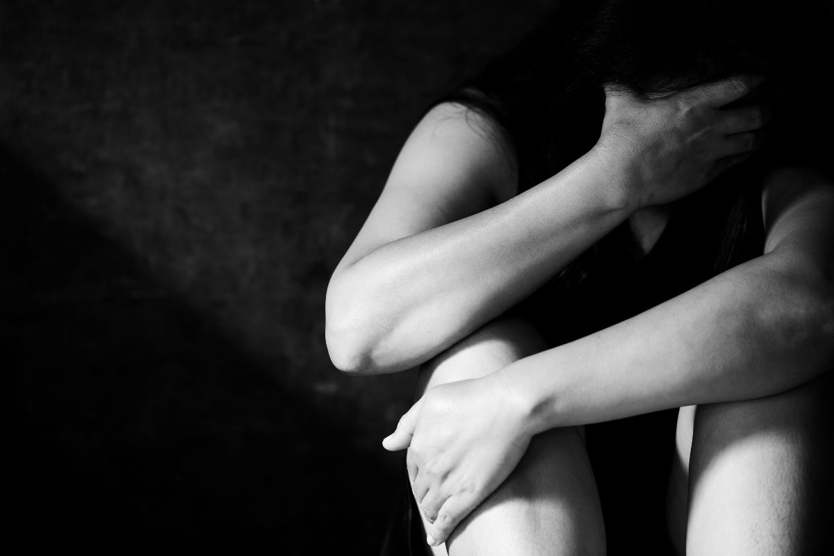 Distressed woman sitting with head in hand.