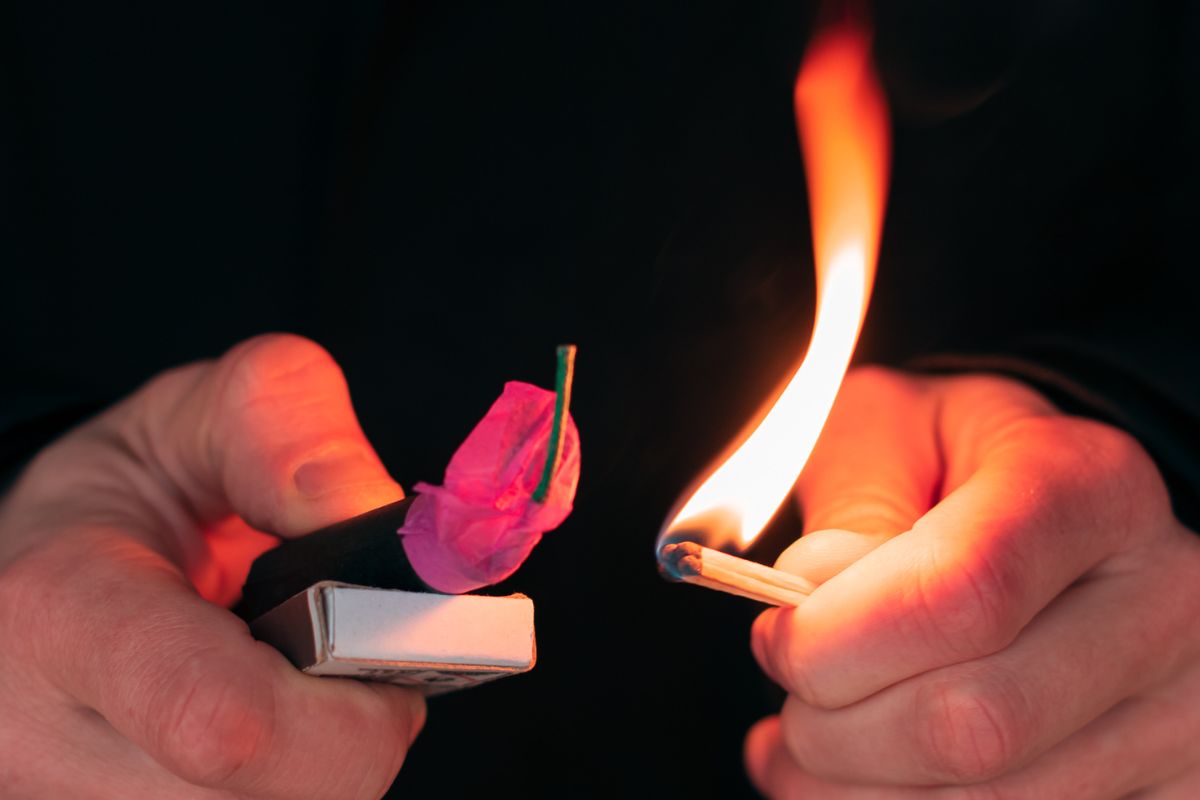 A person lighting a match near a fuse.