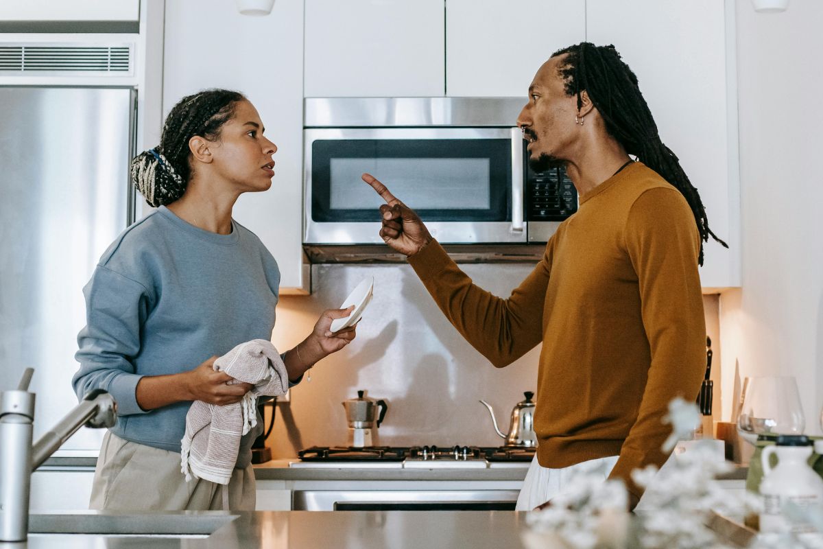 Annoyed man threatening his girlfriend during a conflict in the kitchen.
