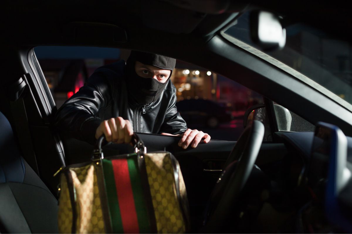 A masked person is stealing a handbag.