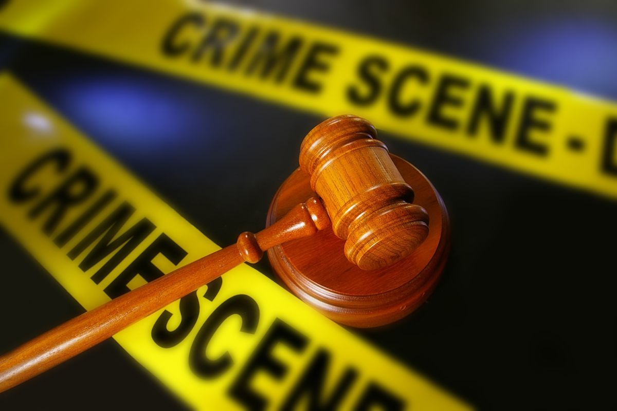Judge’s gavel placed in front of yellow crime scene tape.