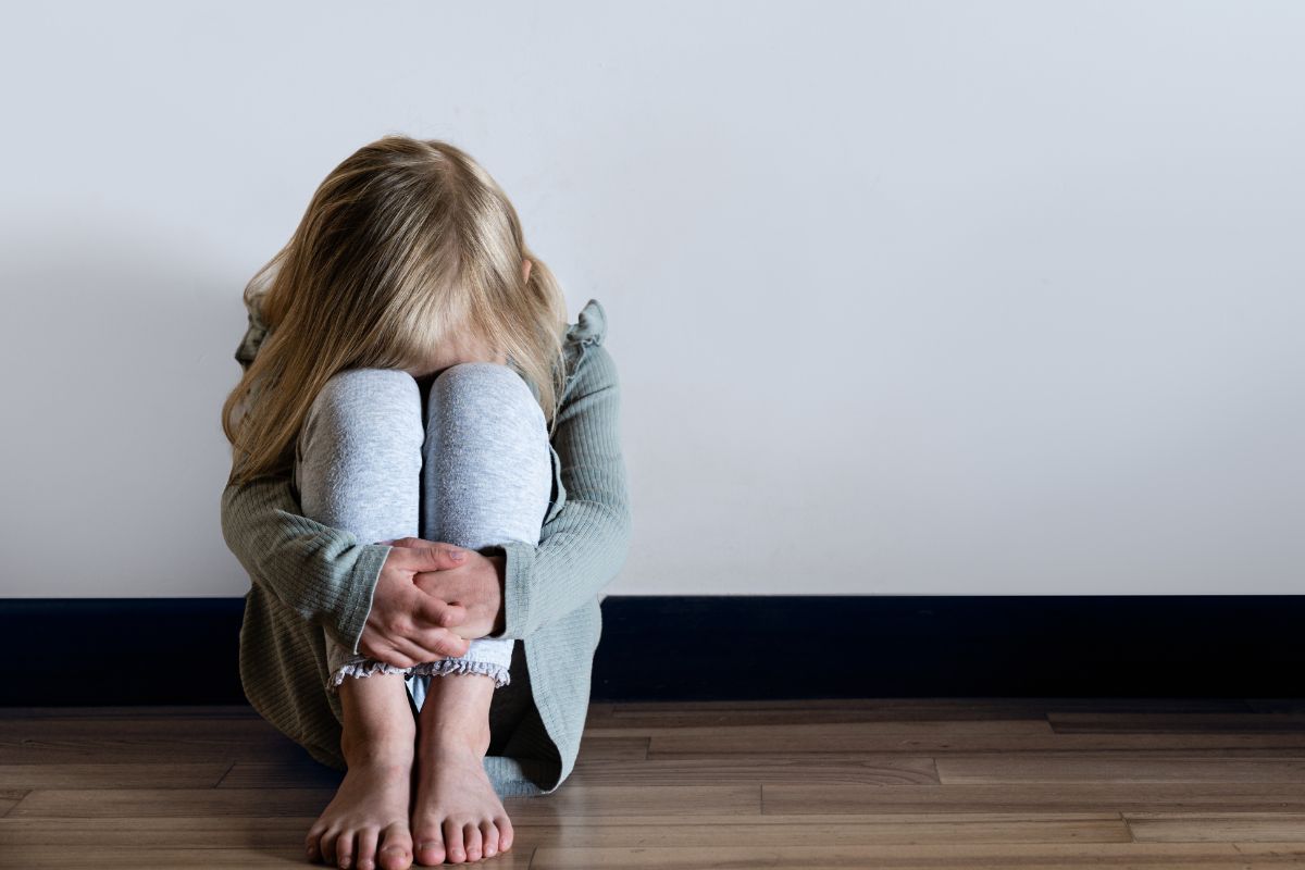A scared young girl sitting on the floor.